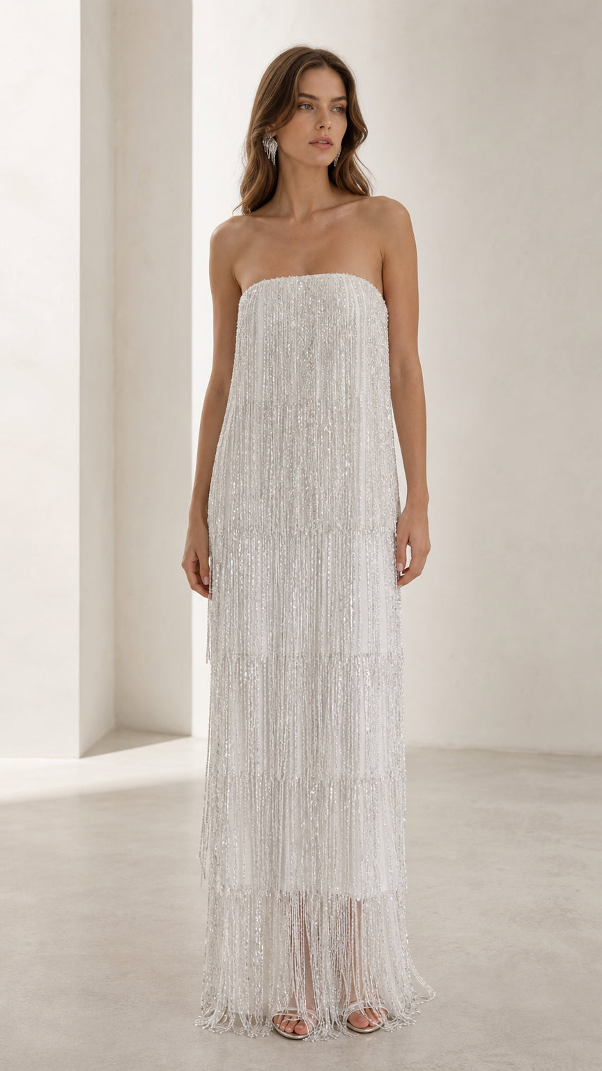 Front view of woman wearing white strapless beaded fringe maxi dress