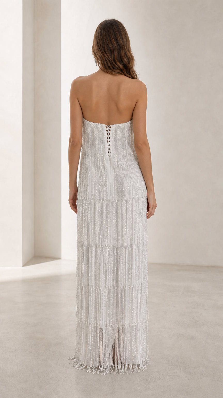 Back view of woman showing lace-up detail on white fringe dress