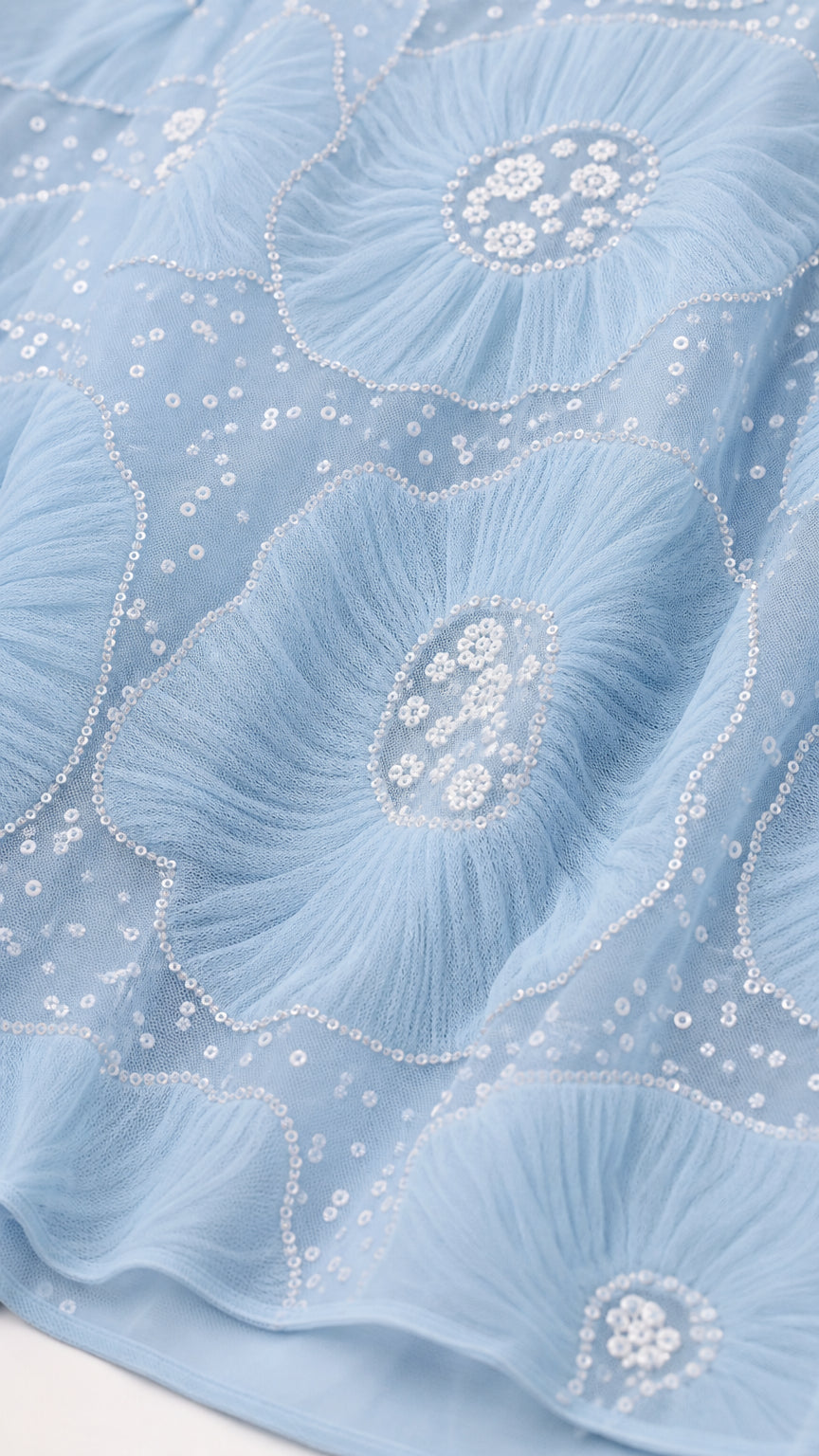 Close-up of light blue fabric showing textured floral embroidery details