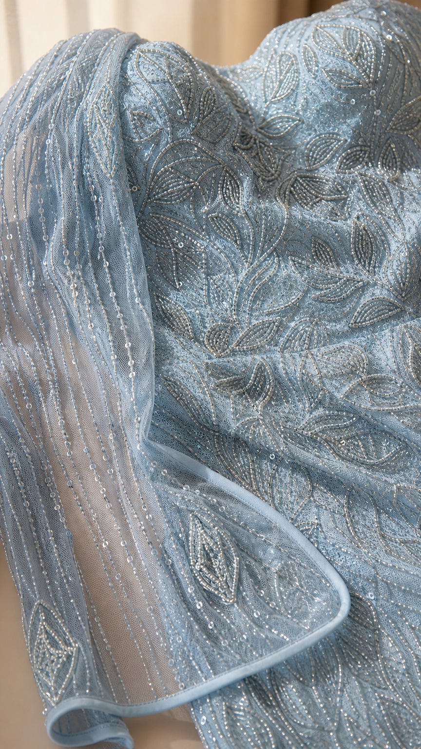 Close-up detail of light blue sequin and bead embroidered mesh fabric