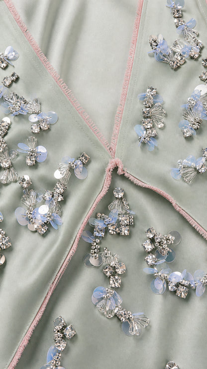 Close-up detail of rhinestone and sequin floral embellishments on sage green dress