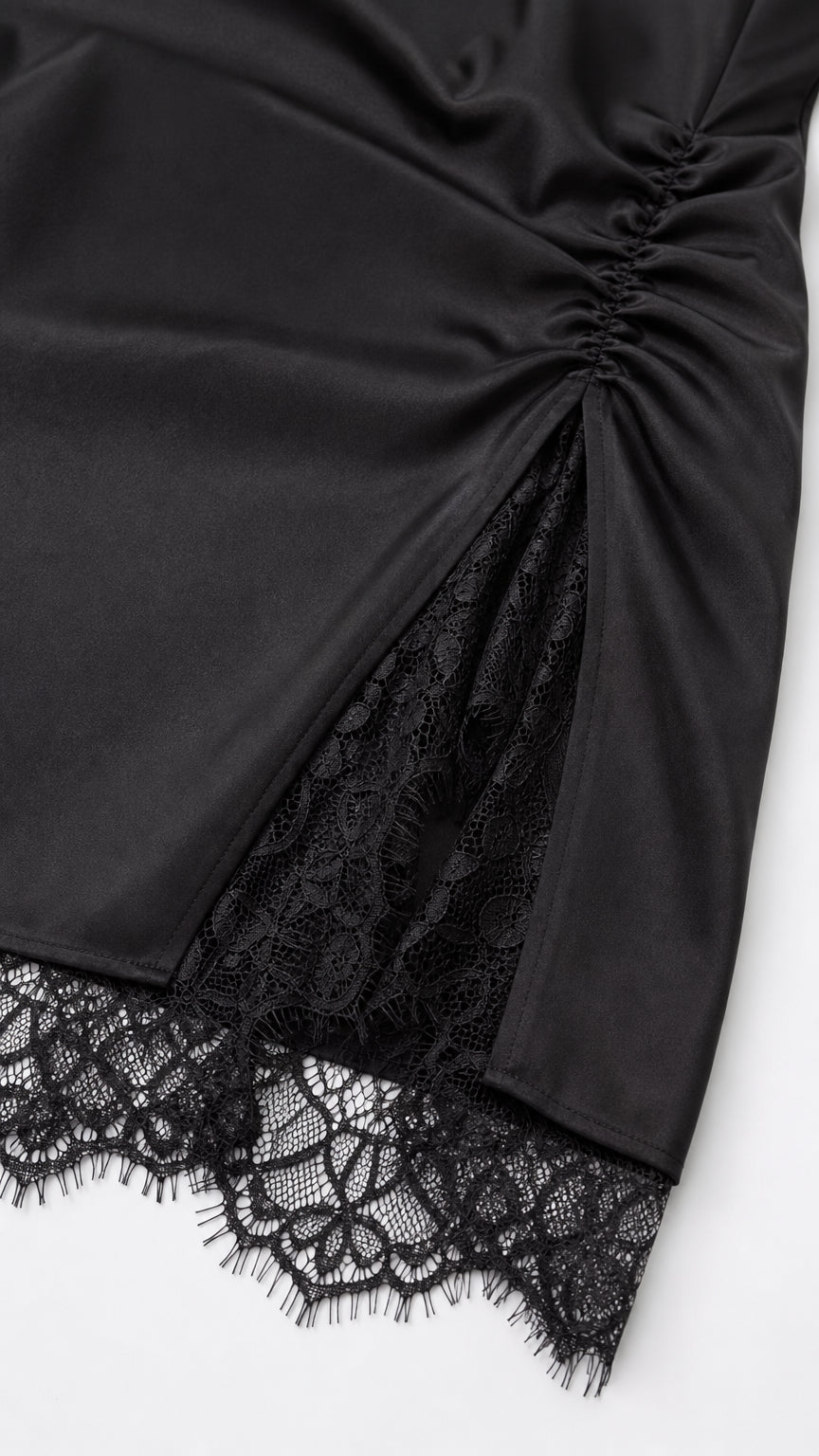 Close-up detail of side ruching and lace slit on black satin dress