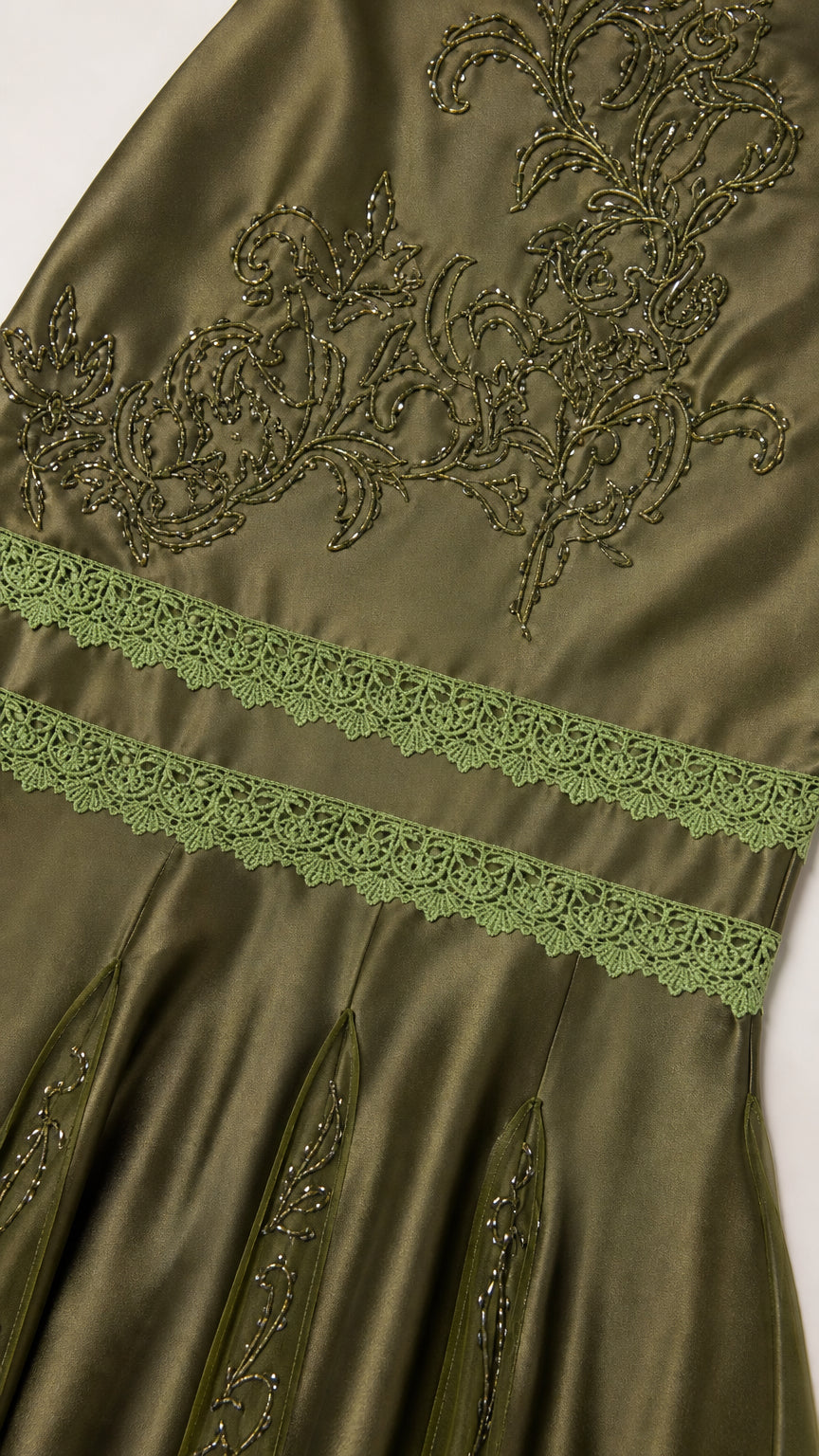 Close-up detail of bodice embroidery and lace trim on olive dress