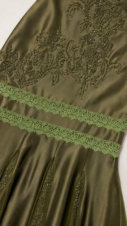 Close-up detail of bodice embroidery and lace trim on olive dress