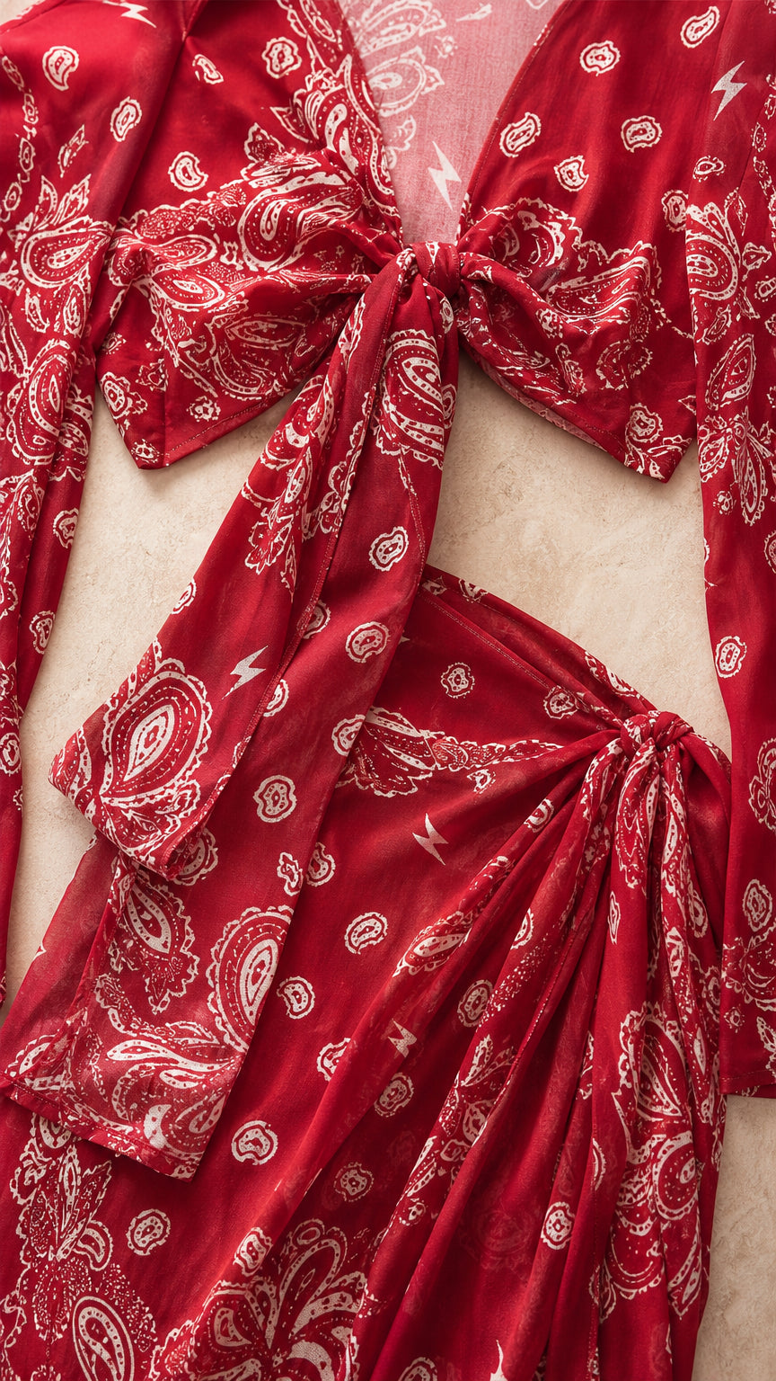 Close-up detail of red paisley fabric, tie-front top, and side-tie skirt