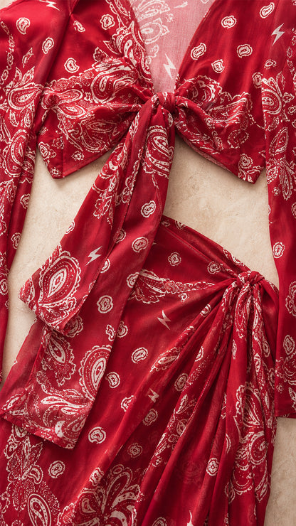 Close-up detail of red paisley fabric, tie-front top, and side-tie skirt