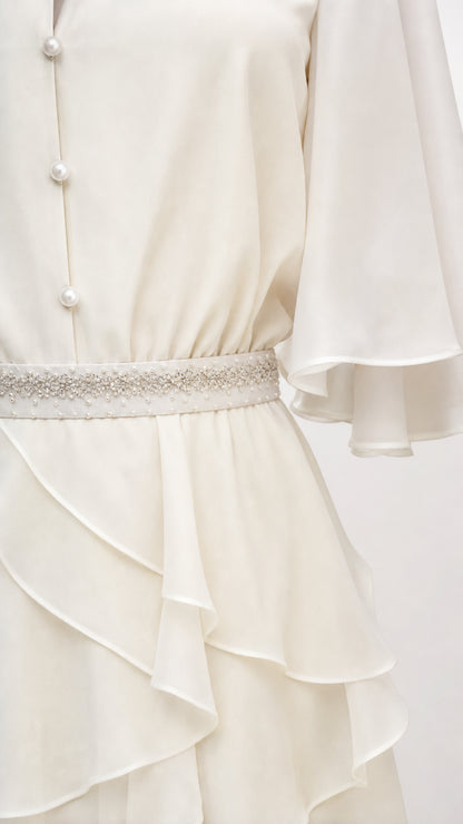 Close-up of pearl buttons and belt detail on white dress