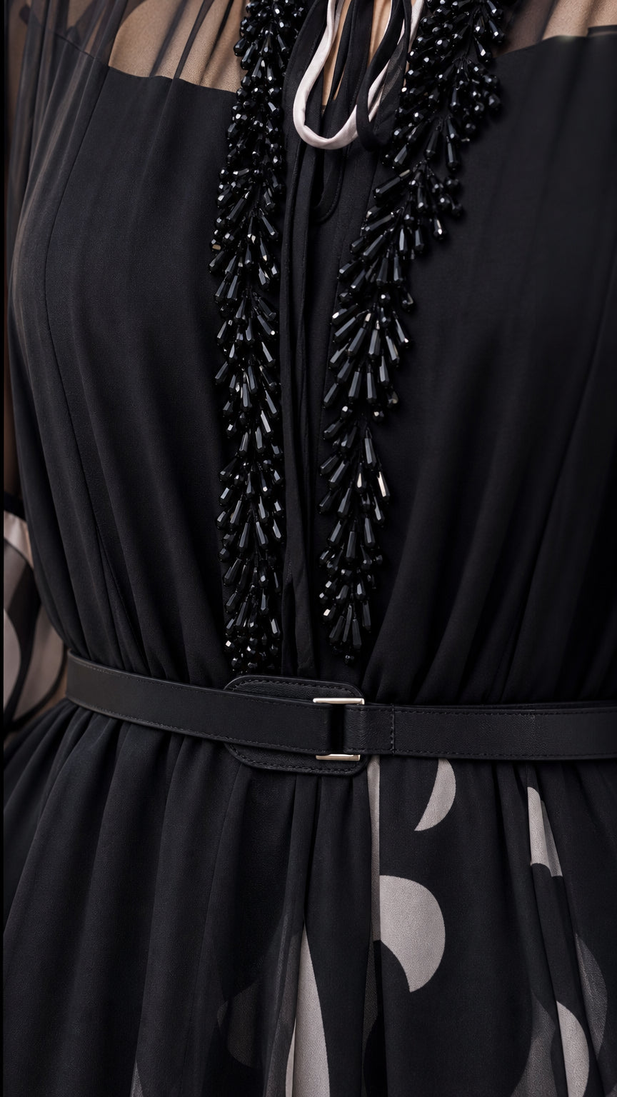 Close up of black chiffon dress neckline showing beaded fringe detail and belt