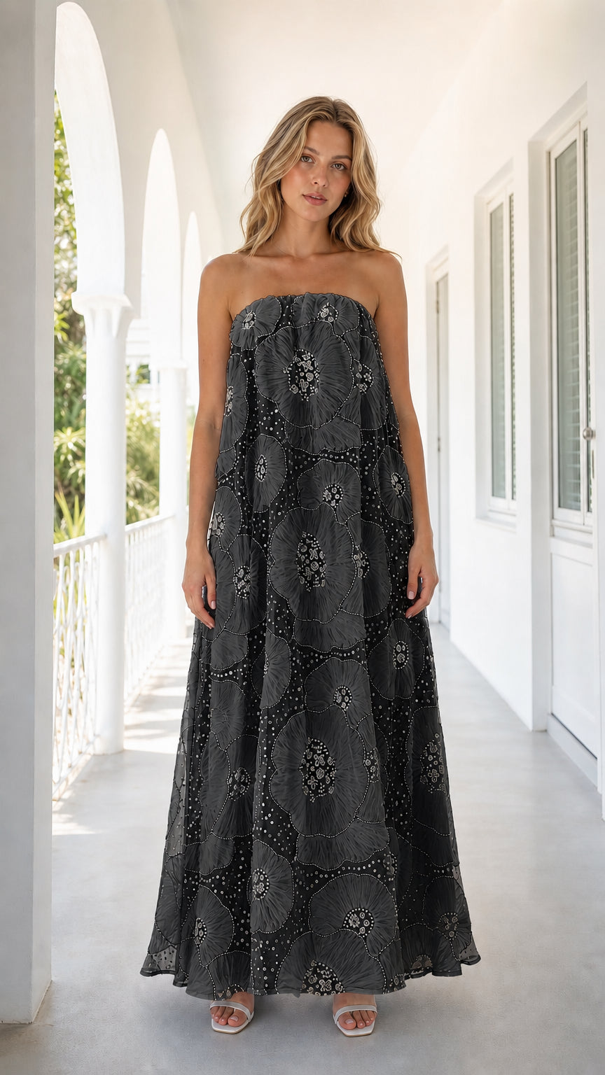 Front view of woman wearing black strapless embroidered floral maxi dress