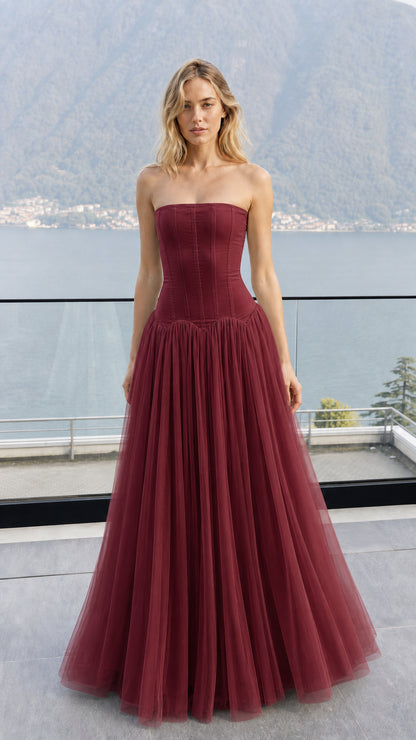 Front view of model wearing burgundy strapless corset tulle maxi dress