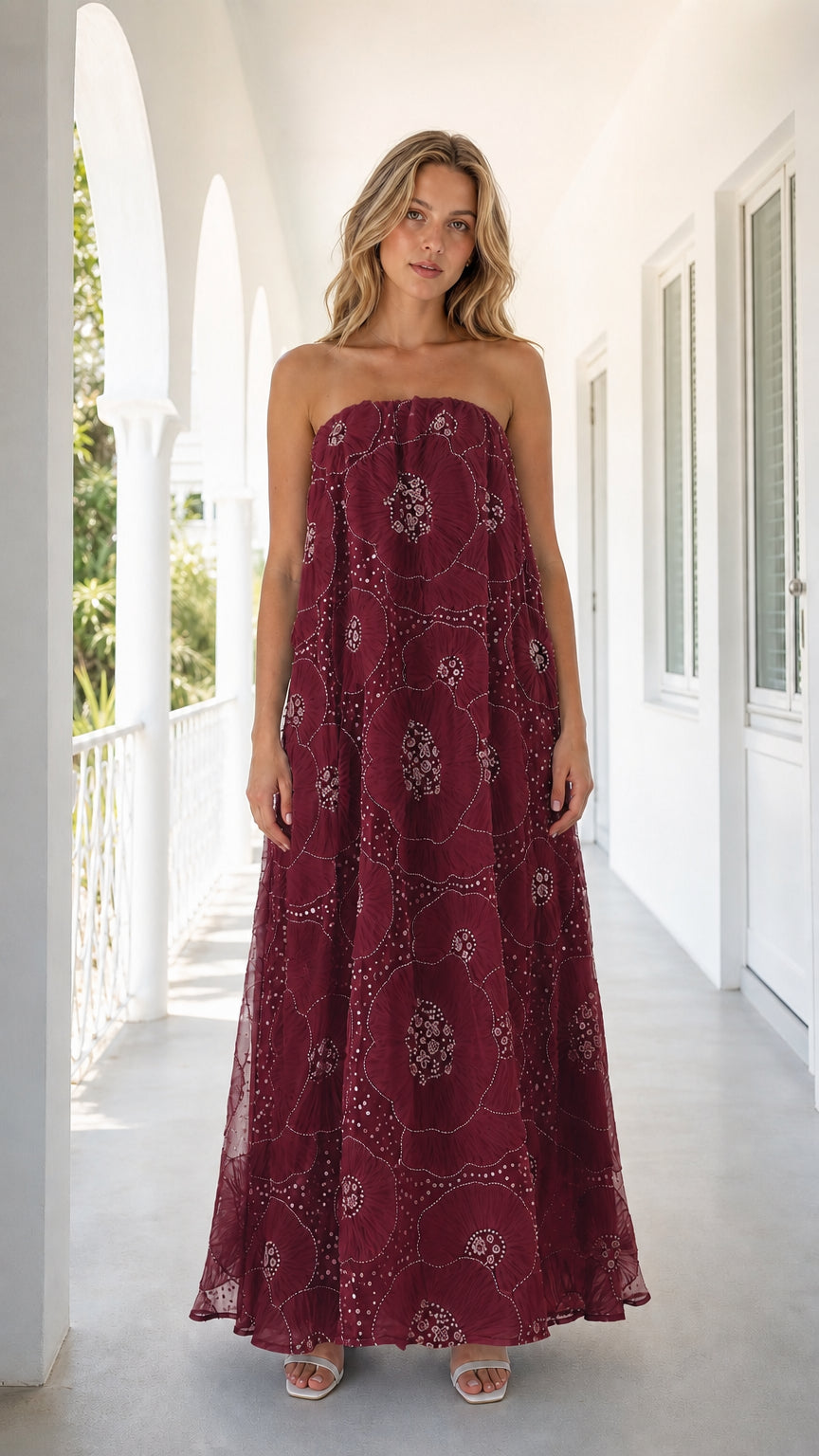 Front view of woman wearing burgundy strapless embroidered floral maxi dress