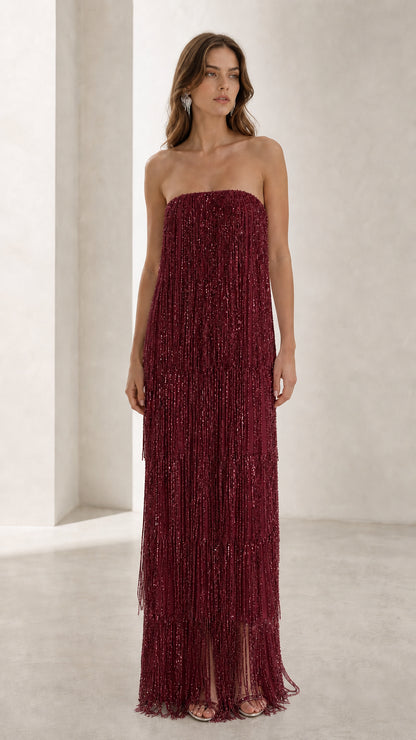 Full view of woman in burgundy red strapless beaded fringe maxi dress