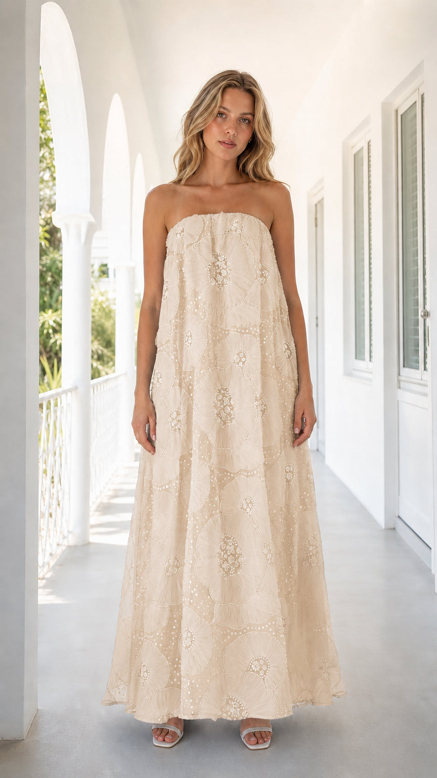 Front view of woman wearing beige strapless embroidered floral maxi dress